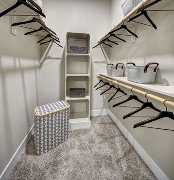 A white closet with a trash can and hangers at Arise Riverside Apartments, Texas